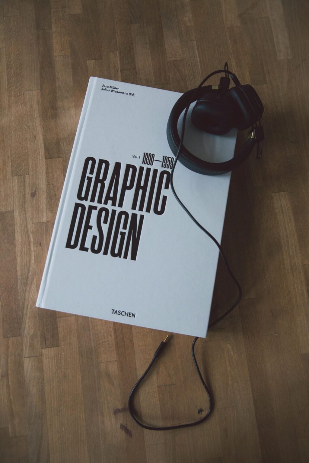 Discover graphic design history with this book and headphones on a wooden floor.